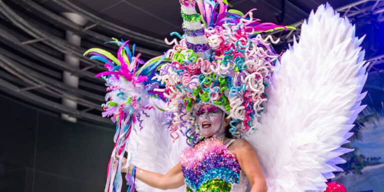 Colorful carnival performer with elaborate feathered headdress and vibrant costume, showcasing the festive spirit of Key West Boat Rentals events and entertainment.