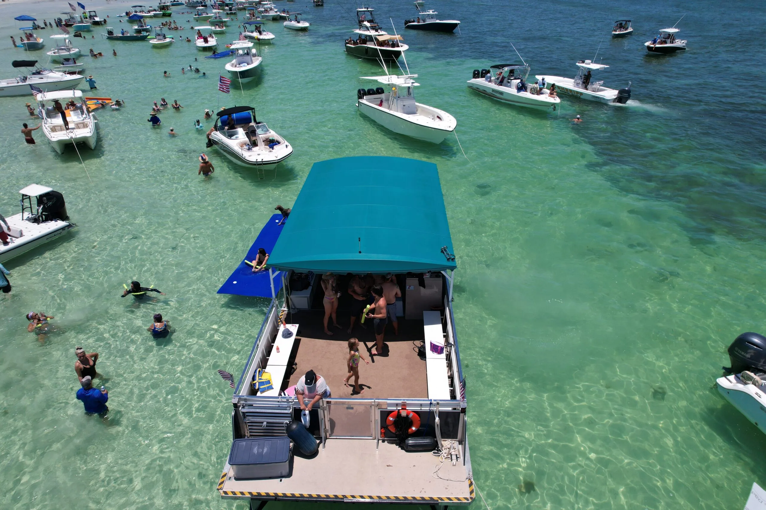 Pontoon boat anchored at a Key West sandbar with swimmers and nearby boat rentals, tiki boat charters, and private trips visible