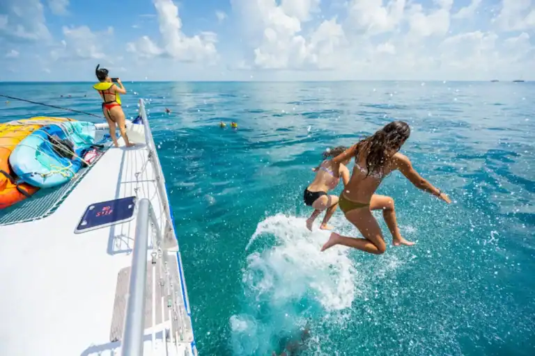 People jumping into the water from a Key West boat rental, enjoying a fun day of swimming and water sports in the clear ocean.