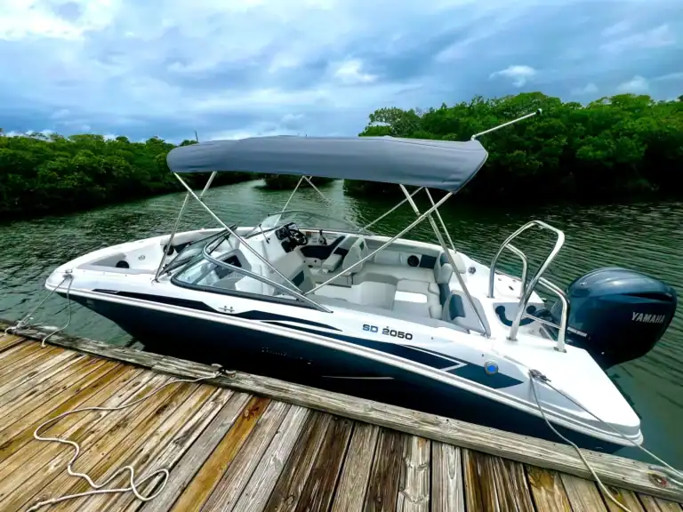 Sleek Key West boat rental yacht docked at a wooden pier with lush greenery and cloudy sky in the background, perfect for exploring Florida's waters.