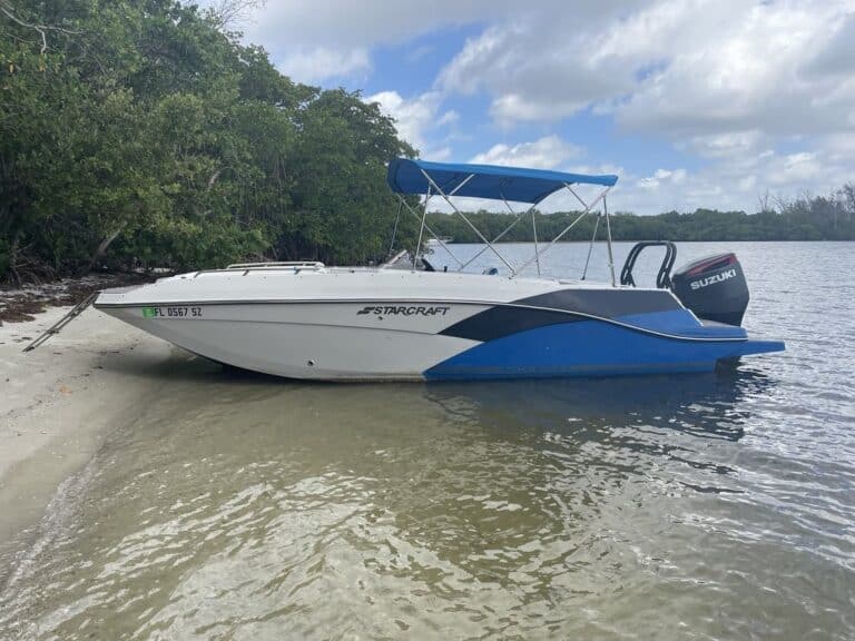 Sunny day at Key West Boat Rentals showcasing a sleek Starcraft motorboat docked near a mangrove shoreline. Perfect for exploring the waters of the Florida Keys.